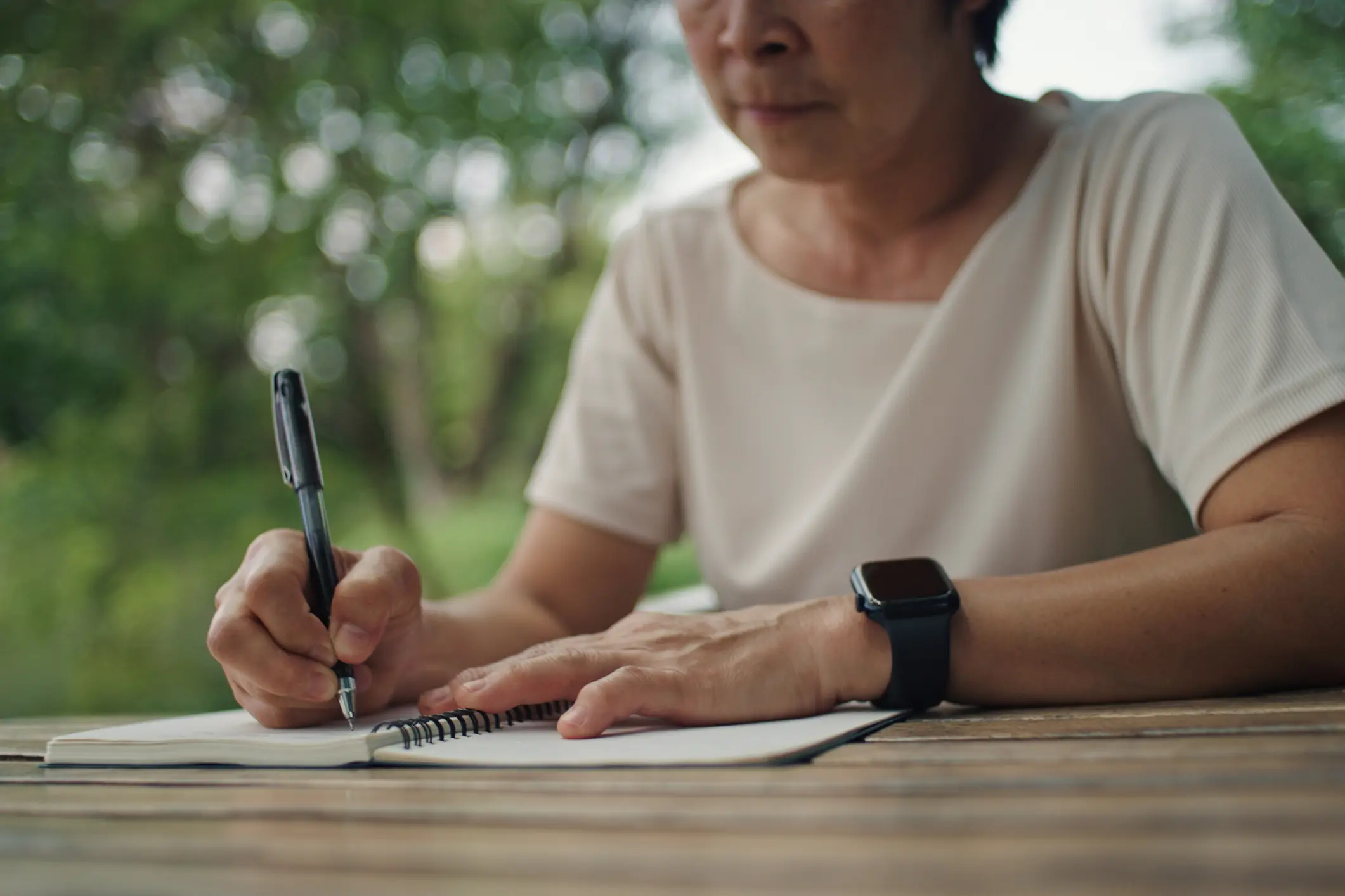 Person writing in a notebook outdoors.